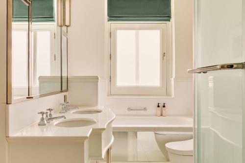a white bathroom with a sink and a toilet at The Connaught, Maybourne in London