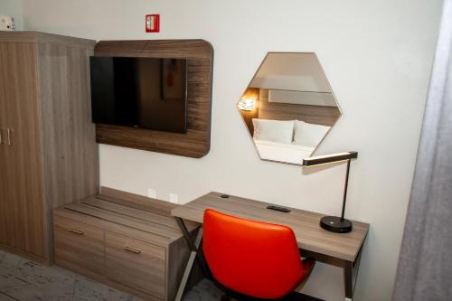 a room with a desk and a tv and a red chair at Holiday Inn Express Tucson-Airport by IHG in Tucson
