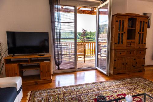 a living room with a television and a sliding glass door at Seeapartments Hörzendorf in Hörzendorf