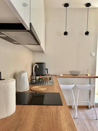a kitchen with a sink and a counter with stools at Lumière Carmela in Corfu