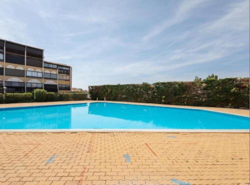 une grande piscine bleue devant un immeuble dans l'établissement Cap d'agde naturiste 2 pers, au Cap d'Agde