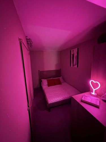 Cette chambre violette comprend un lit et une table de nuit. dans l'établissement Cap d'agde naturiste 2 pers, au Cap d'Agde