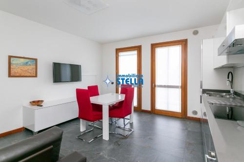 a living room with a table and red chairs at Archimede in Lido di Jesolo