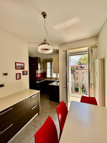 a kitchen with a table and red chairs and a window at Attico del Duomo Historic Center & Free Wi-Fi in Asti