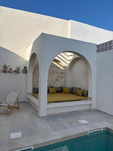 a bed on a patio next to a swimming pool at Villa Eden Djerba in Djerba