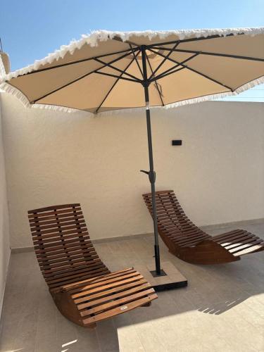 two chairs under an umbrella on a patio at Villa Eden Djerba in Djerba