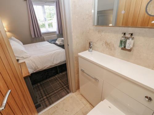 ein Badezimmer mit Waschbecken und Spiegel und einem Bett in der Unterkunft Cosy Cottage 4 in Durham
