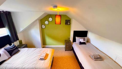 a attic room with two beds and a green wall at Luxury 5-Bed Home in Nicholson, Close to Sheffield City Centre, Jacuzzi, BBQ, Parking & Wi-Fi, Sleeps 10 in Heeley