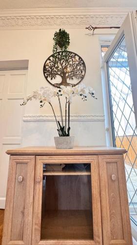 a wooden cabinet with a vase with flowers on it at Luxury 5-Bed Home in Nicholson, Close to Sheffield City Centre, Jacuzzi, BBQ, Parking & Wi-Fi, Sleeps 10 in Heeley
