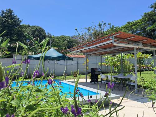 a swimming pool with a pergola and a table and a picnic table at Centro Vacacional el Amanecer in Puntarenas