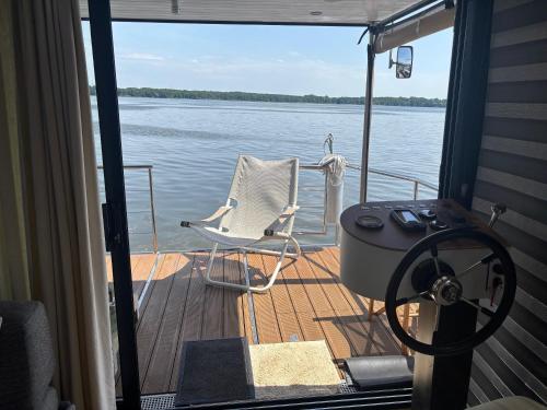a chair sitting on the deck of a boat at WOHLFÜHLBOOT Hausboot - Festlieger in der Marina Zaue am Schwielochsee - incl Stand Up Board in Schwielochsee