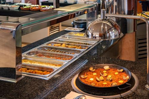 a buffet line with trays of food on a counter at 4R Casablanca Playa in Salou