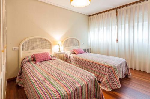 two beds in a room with striped sheets at Apartamentos Cotiello in Llanes