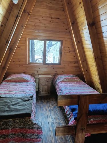 two beds in the attic of a log cabin at Alpinas Aliwé in San Ignacio