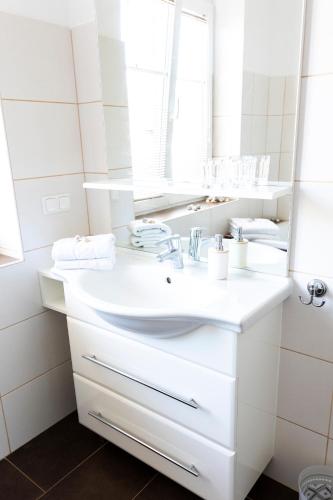 a white bathroom with a sink and a mirror at Seeapartments Hörzendorf in Hörzendorf