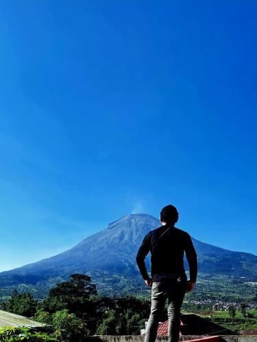 a man standing in front of a mountain at Griya Laksita Haven Dieng in Kejajar