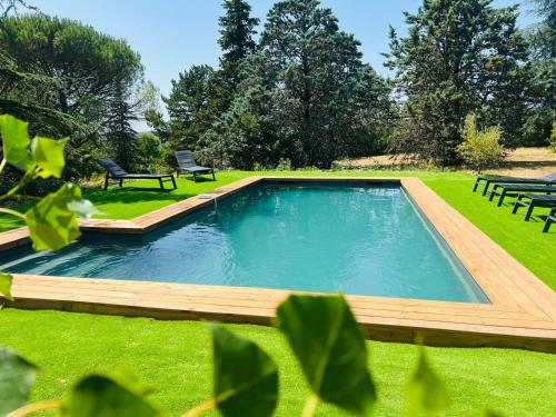 a swimming pool in a yard with two benches at Villa Les Roques in Saint-Vincent-Rive-dʼOlt