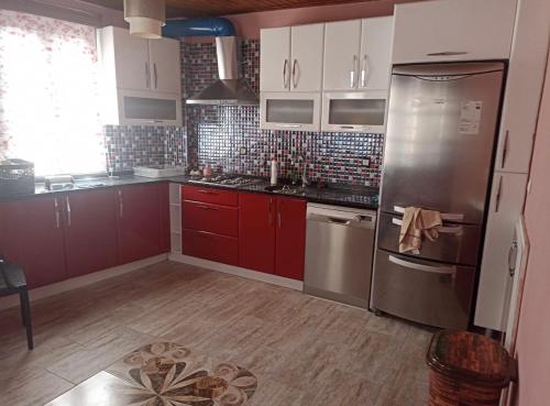 a kitchen with red cabinets and a stainless steel refrigerator at Altun Konak in Ayvalık