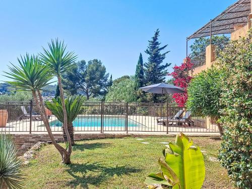 une piscine dans une cour avec des palmiers et une clôture dans l'établissement Apartment Douce parenthése-2 by Interhome, à Sanary-sur-Mer