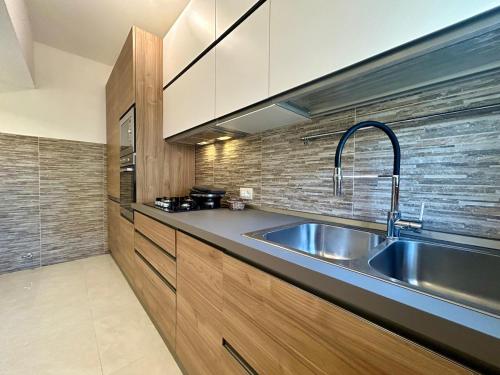 a kitchen with a stainless steel sink and wooden cabinets at Comfort & design - 20' dalle terme di Saturnia in Manciano