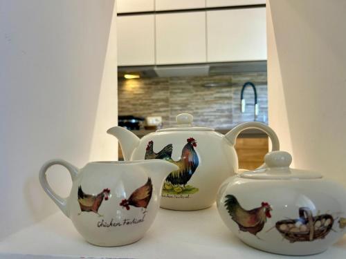 three white teapots with chickens on them on a counter at Comfort & design - 20' dalle terme di Saturnia in Manciano