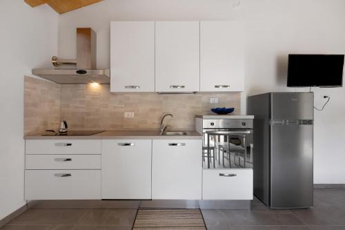 a kitchen with white cabinets and a stainless steel refrigerator at Agriturismo Le Macere in Sasseta