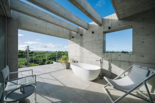 a bathroom with a tub and a sink and chairs at villa irifi 夕陽を望むヴィラ in Miyako Island