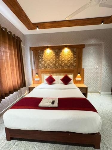 a bedroom with a large bed with two red pillows at Crystal inn BY D2V in Kakkanad
