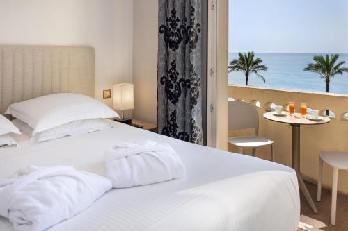 a bedroom with a white bed with a view of the ocean at Hotel Royalmar - Nouveau propriétaire in Cagnes-sur-Mer