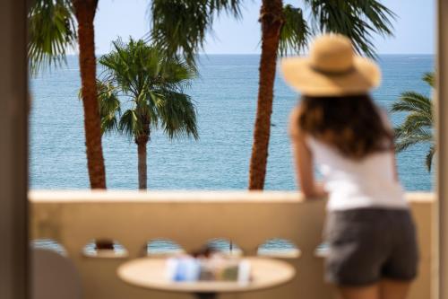 a woman in a hat looking out at the ocean at Hotel Royalmar - Nouveau propriétaire in Cagnes-sur-Mer