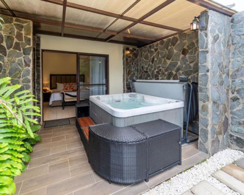 a hot tub on a patio with a stone wall at Hotel & Spa Poco a Poco - Costa Rica in Monteverde Costa Rica