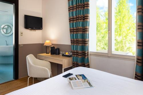 a hotel room with a bed and a desk and a window at Hotel Royalmar - Nouveau propriétaire in Cagnes-sur-Mer