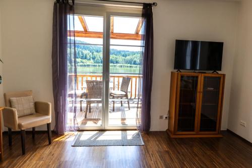 a living room with a tv and a sliding glass door at Seeapartments Hörzendorf in Hörzendorf