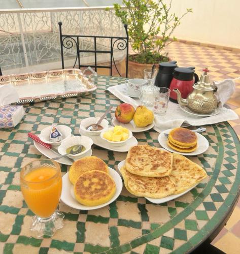 Riad Lalla Aicha في مراكش: طاولة مليئة بأطباق الفطائر وعصير البرتقال