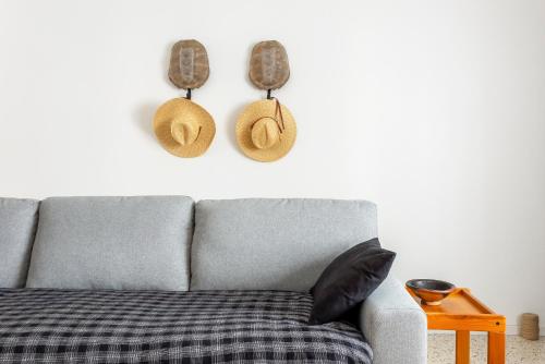 a couch with hats hanging on a white wall at Le Patio des Salins - Sublime maison de charme intramuros à Aigues-Mortes in Aigues-Mortes