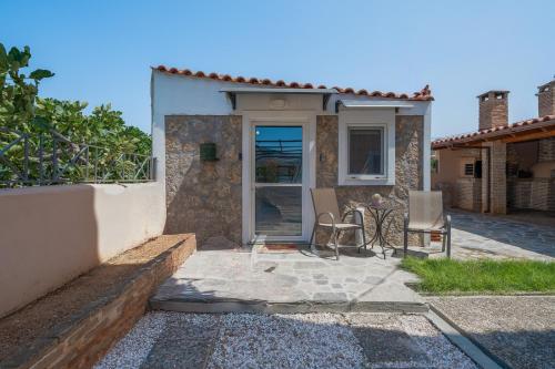 a house with a door and two chairs outside at Villa Clotho in Porto Rafti