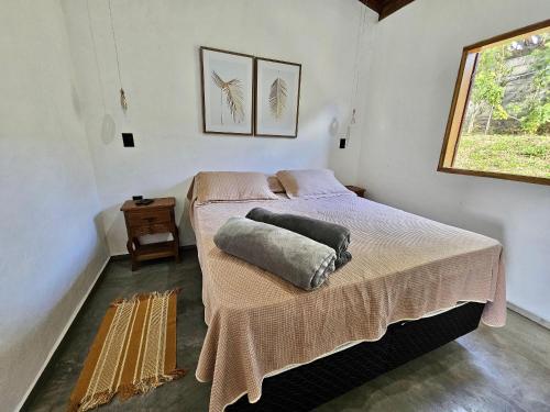 a bedroom with a bed with a blanket and a window at Chalés Vila Carrancas - Ao lado do centro com piscina, cozinha completa e muita tranquilidade in Carrancas