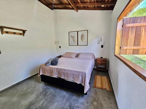 a bedroom with a bed in a room with a window at Chalés Vila Carrancas - Ao lado do centro com piscina, cozinha completa e muita tranquilidade in Carrancas