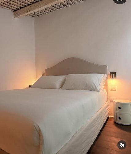 un lit avec des draps blancs et des oreillers dans une chambre dans l'établissement CoDe24, à Noto