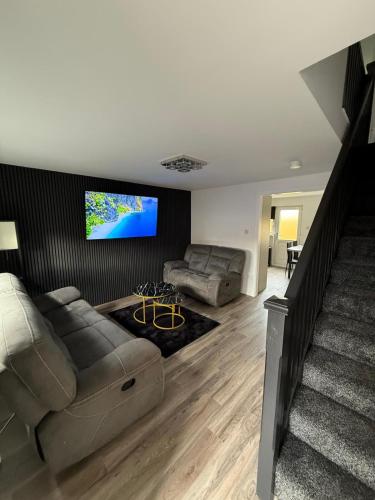 a living room with a couch and a flat screen tv at Home Comfort Prestwick in Prestwick