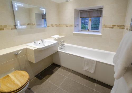 a bathroom with a tub and a sink and a toilet at Cottage No1 Four Bed Lakeland Retreat and Hot Tub in Elterwater