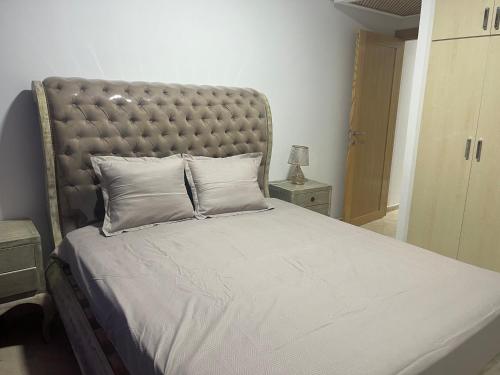 a large bed with a padded headboard in a bedroom at Résidence de standing , appartement à 2 pas de la mer , jardin, piscine Hammamet nord in Nabeul