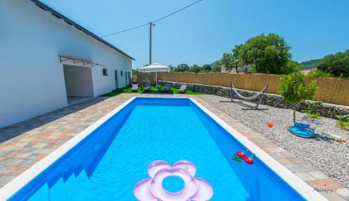 a swimming pool with an inflatable pool toy in a backyard at Holiday Home Blaz in Ljubuški