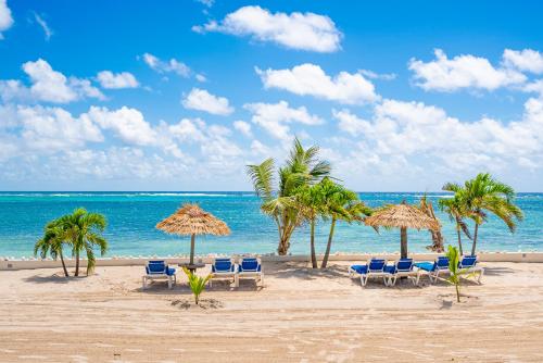 a beach with chairs and umbrellas and the ocean at St. James's Club Resort - All Inclusive in English Harbour Town