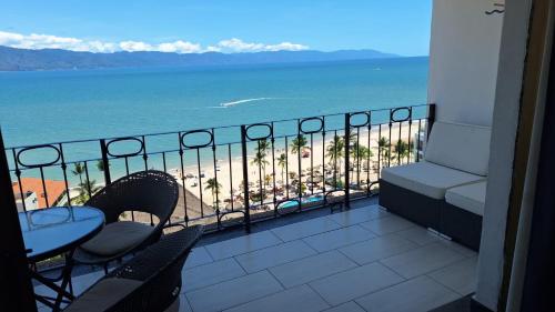 a balcony with a table and chairs and the ocean at Puerto Vallarta Condo Frente al mar in Puerto Vallarta