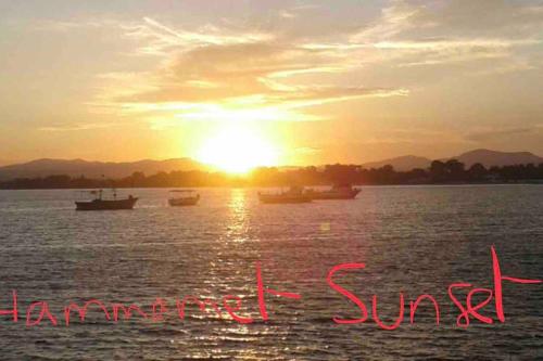 a sunset over a body of water with boats at Résidence de standing , appartement à 2 pas de la mer , jardin, piscine Hammamet nord in Nabeul