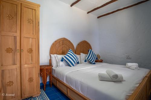 a bedroom with a bed with blue and white pillows at Riad ALHAMBRA in Chefchaouene