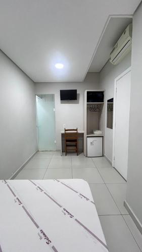 a room with a bed and a table and a television at Hotel Salomão - Próximo a 25 de Março, Bom Retiro, Brás e Rua Santa Efigênia, a 2 minutos do Mirante Sampa Sky e pista de Skate Anhangabaú in Sao Paulo