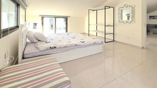 a white bedroom with a large bed and a chair at Tabarja Hills apartment in ‘Ayn aş Şughayrah