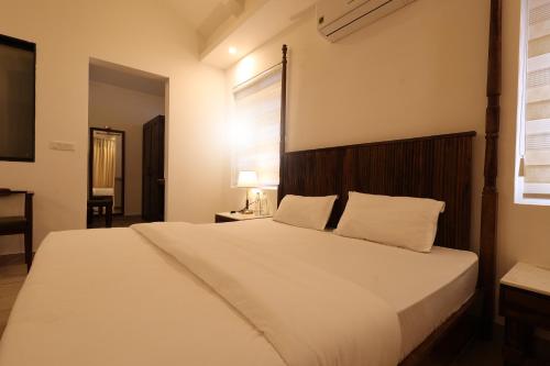 a bedroom with a large white bed and a window at Gubbi Goodu Green Resort in Bengaluru